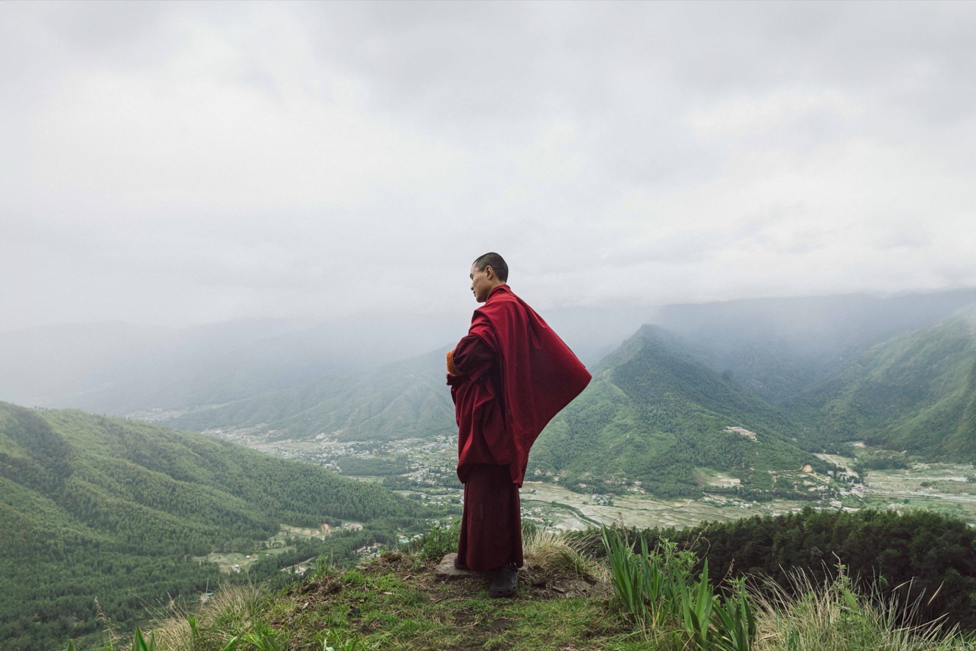 A monk looking out over a mist-filled Bhutanese valley