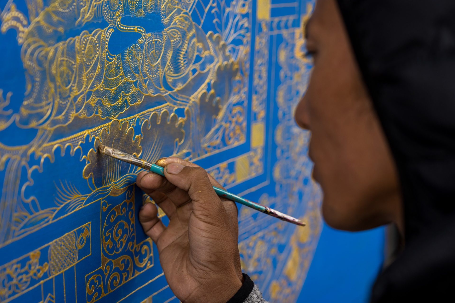 A painter working gold detail onto a thangka in Punakha